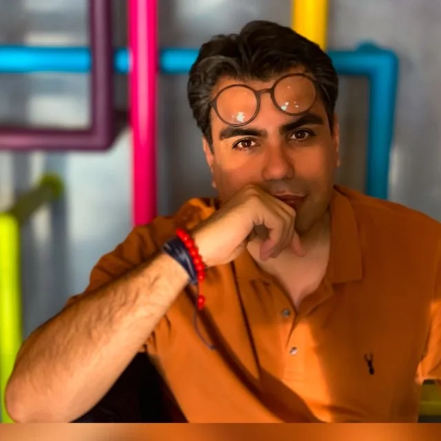 Alireza Rajabi, in an orange shirt, resting his chin on his hand